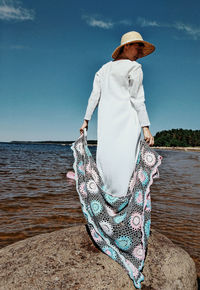 Rear view of woman standing by sea against sky