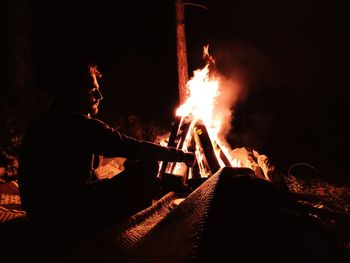 Man sitting by fire at night