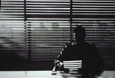 Businessman reading document in office against blinds