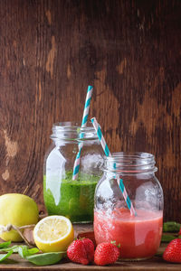 Spinach and strawberry smoothie in jar by fruits against wooden wall
