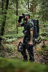 Full length of man holding camera in forest