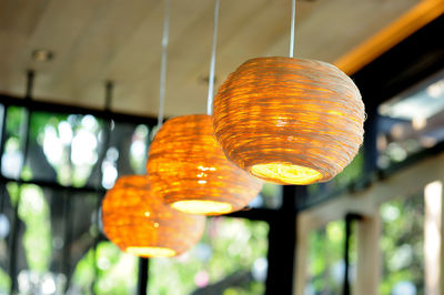 Close-up of illuminated light bulb hanging on ceiling