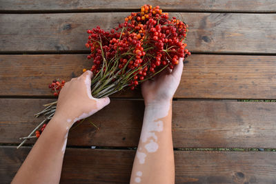 Midsection of woman holding bouquet against wooden table