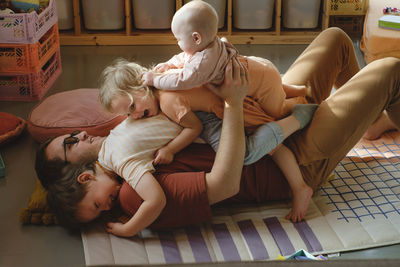 Happy father with tree small kids playing at home. dad cuddling with children, holding them on hands