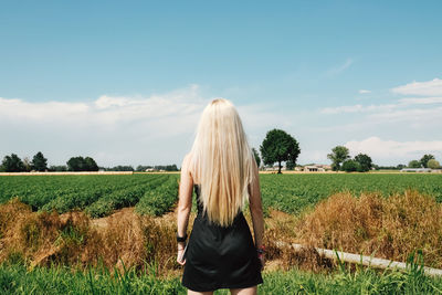 Rear view of woman standing on field against sky