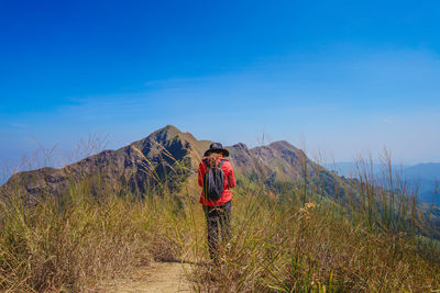 Rear view of man standing on mountain against sky