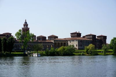 Buildings by river against sky