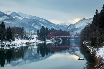 Arch bridge over lake against snowcapped mountains