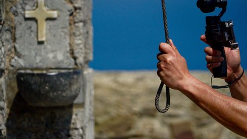 Cropped hand photographing by stone wall