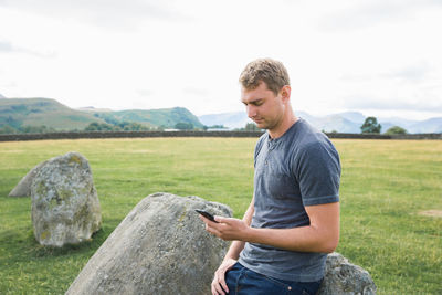 Side view of young man standing on rock