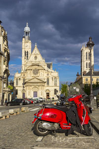 Vehicles on road amidst buildings against sky in city