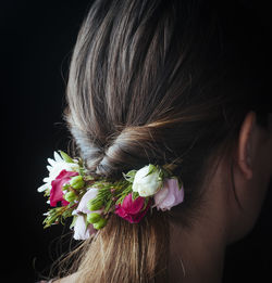 Rear view of woman with roses against black background