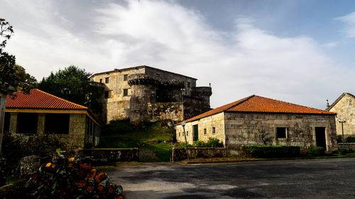 Old houses by road amidst buildings against sky