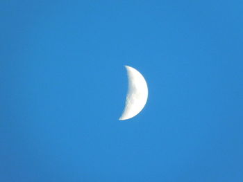 Low angle view of moon against clear blue sky