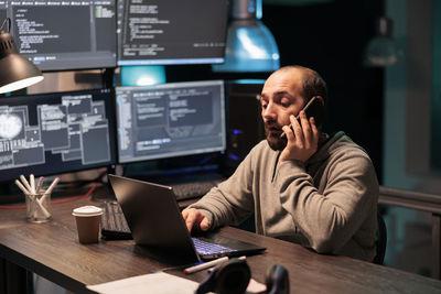 Portrait of man using mobile phone while sitting on table