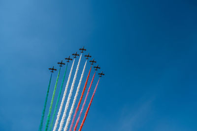 Low angle view of airplanes flying against blue sky