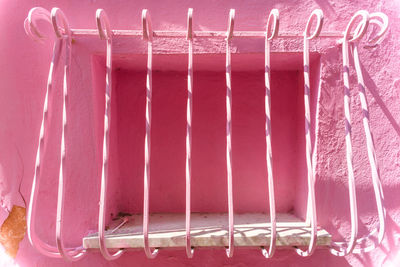 Close-up of metal fence against pink wall