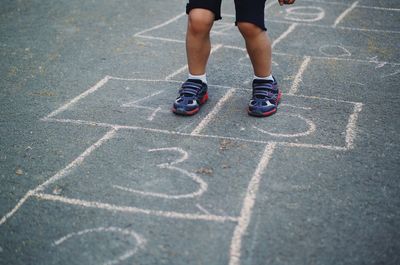 Low section of child playing hopscotch on road
