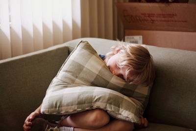 Boy relaxing with cushion on sofa at home