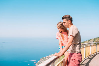 Couple kissing against sea against clear sky