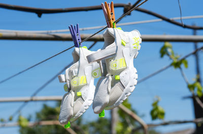 Women's sneakers hang on a rope to dry. pair of white sneakers hanging on pegs