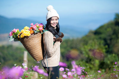 Smiling woman carrying flowers in basket