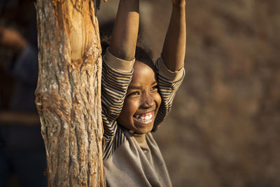 Full length of happy boy on tree trunk
