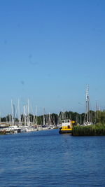 Sailboats on sea against clear blue sky