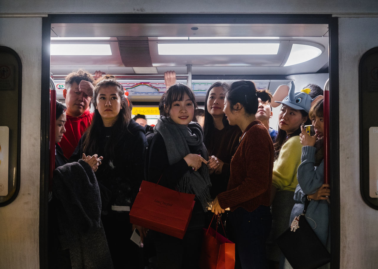 group of people, public transportation, real people, rail transportation, men, train, mode of transportation, transportation, standing, three quarter length, people, lifestyles, train - vehicle, casual clothing, women, group, adult, crowd, commuter, subway train, commuter train