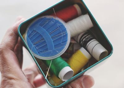 Close-up of person holding spools in container