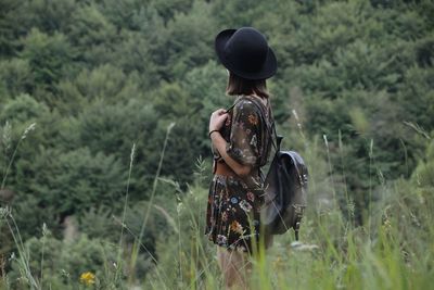 Rear view of person wearing hat standing on field