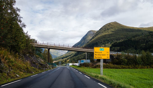 Road leading towards mountains against sky