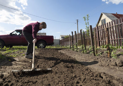 Man working on agricultural field against sky