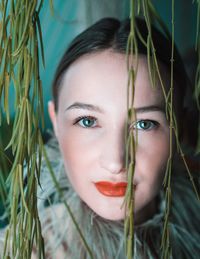 Close-up portrait of young woman with plant