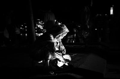 Woman with illuminated light sitting on road at night