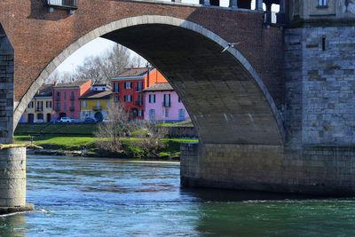 Arch bridge over river against buildings