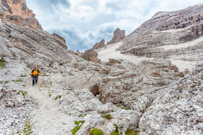 Rear view of person walking on rock against sky