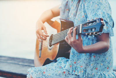 Midsection of woman playing guitar