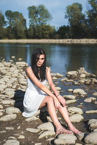 Portrait of beautiful woman sitting on rocks by river