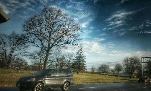 Cars parked on road against cloudy sky