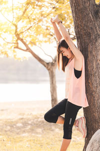 Woman standing by tree trunk