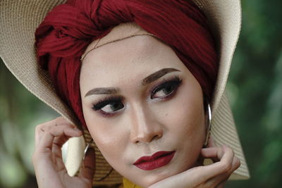 Woman looking away while wearing hat against trees