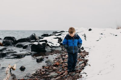 Boy walking at lakeshore on during winter