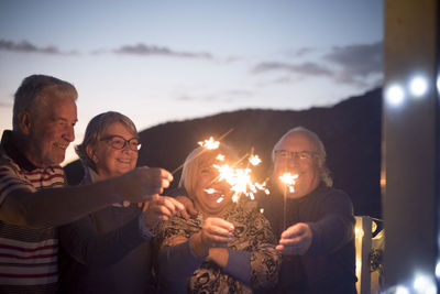 People holding illuminated lighting equipment at night