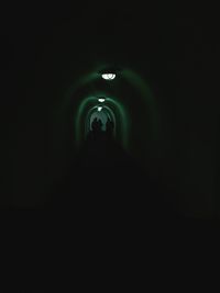 Silhouette people walking in illuminated tunnel