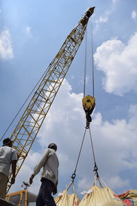 Low angle view of crane at construction site against sky