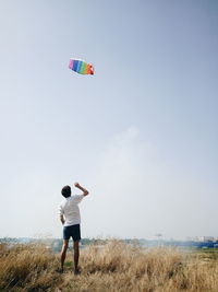 Rear view of man flying kite against clear sky