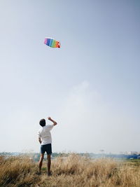 Rear view of man standing on field against sky