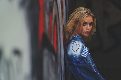 Portrait of woman standing against wall