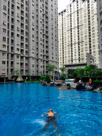 Man swimming in pool against buildings